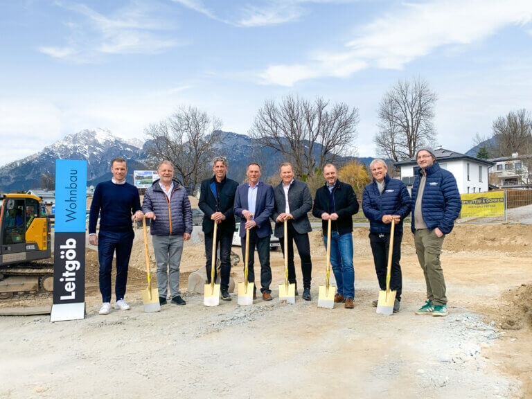 Gruppenfoto von Leitgöb Wohnbau mit Schaufeln auf Baustelle in den Alpen.
