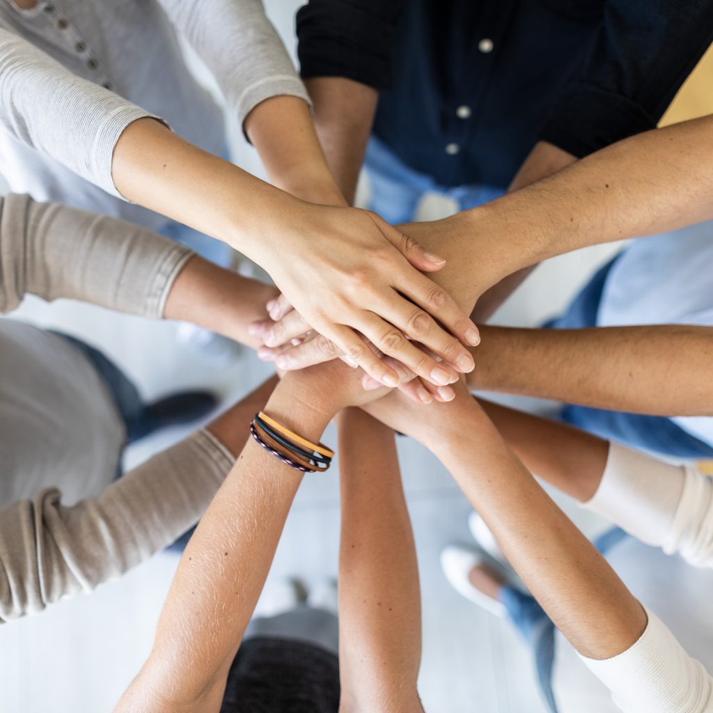 Mehrere Menschen legen ihre Hände übereinander als Zeichen für Teamwork