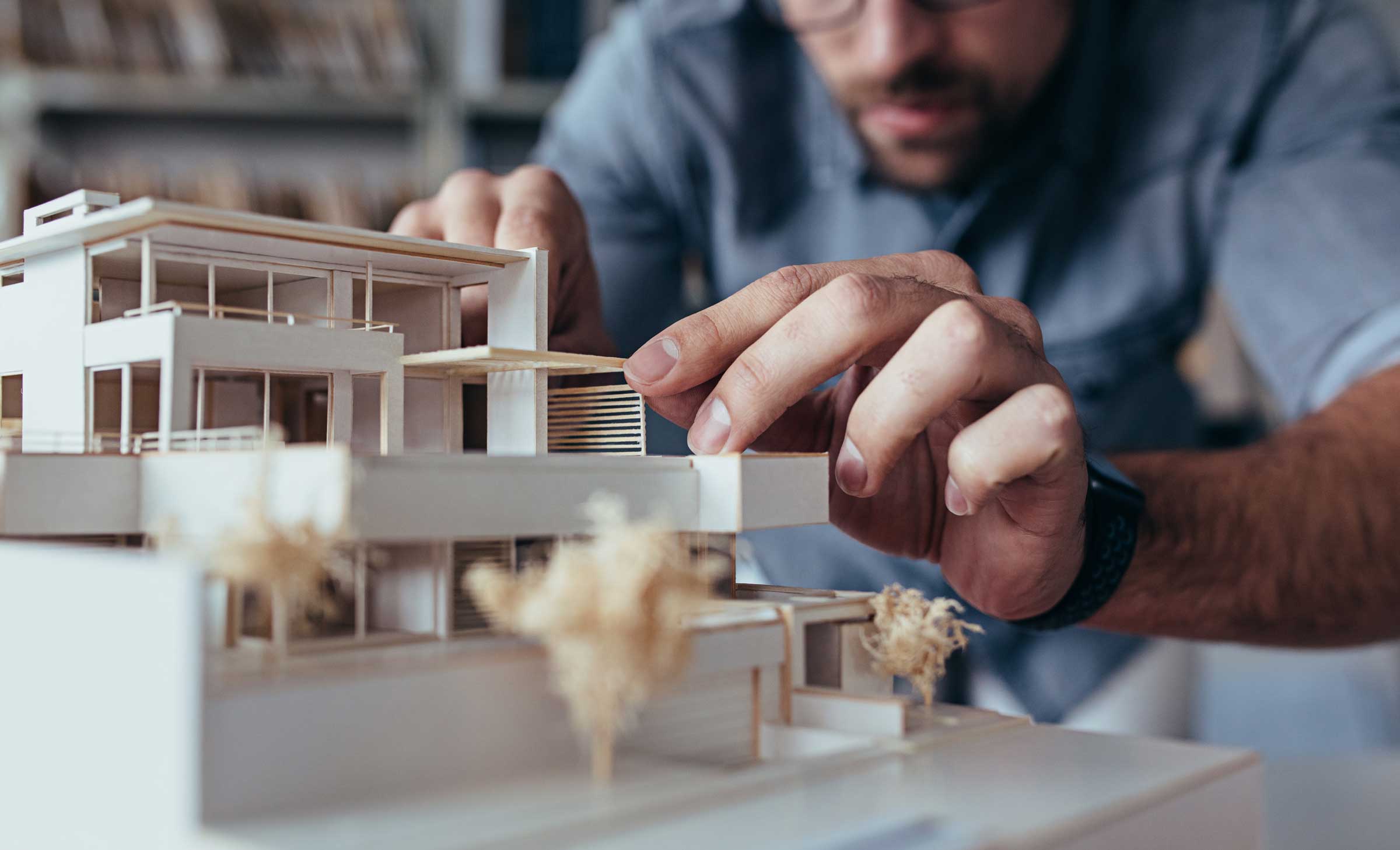 Planung-Modell_2400px Mitarbeiter der Planung bei der Detailarbeit an einem Architekturmodell eines modernen Wohngebäudes.