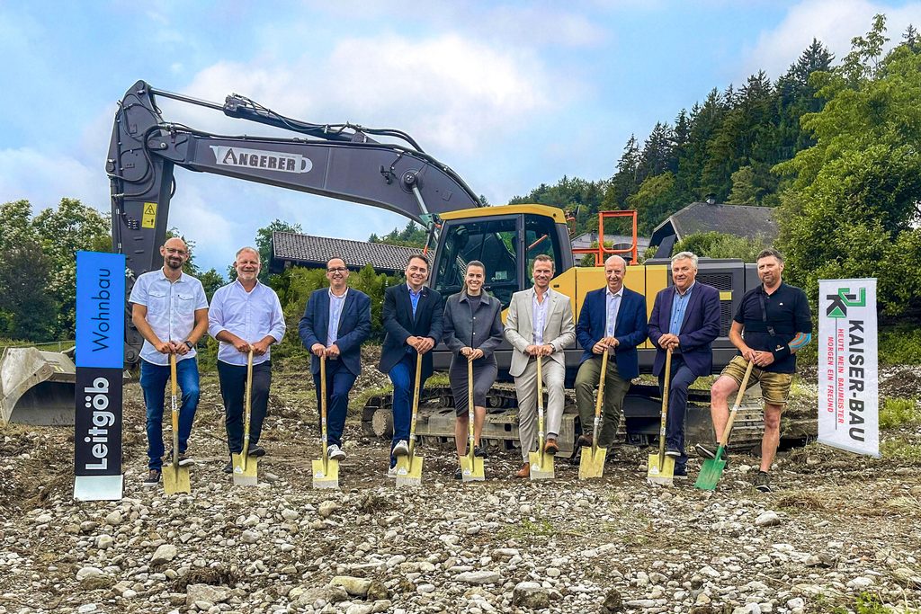 Gruppe mit Spaten vor Bagger beim Spatenstich Plainfeld auf einer Baustelle