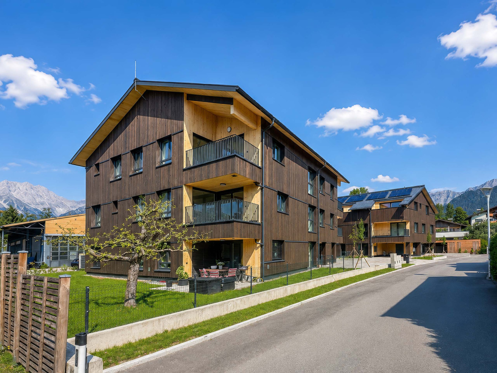 Moderne Wohnhäuser mit dunkler Holzfassade, Balkonen und Bergkulisse in Saalfelden